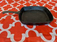 Square cast iron skillet showing top side with handle and cooking surface.