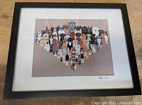 Photo of the framed stylized print depicting dozens of different dog breeds arranged in a triangular shape, showing various colors and dog breed features.