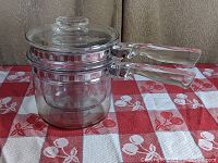 Front angle view of the full double boiler set resting on a red and white patterned cloth.