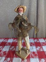 Front view of the folk art paper fisherman statue with net and fish.