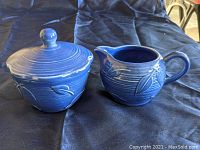 Photo showing both the blue creamer and sugar bowl with lid, highlighting design and color.