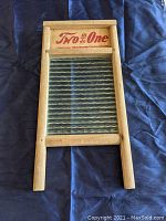 Full view of washboard showing wooden frame, glass scrubbing surface, and printed brand name on wood.