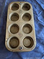 Top side of Ekco muffin pan showing 8 round baking cups with some rust spots and wear marks.