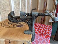 Close-up photo showing the cast iron clamp and crank handle attachment to table edge.