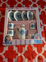 Full view of the toy china set in original box, showing all components arranged neatly including coffee pot, creamer, sugar bowl, 2 plates, 2 cups, and 2 saucers with blue floral pattern.