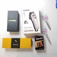 Photo of all items showing AUDOC hair clipper box, Belula hair brush box, Mane Jack beard grooming set box and leather case, black box hair trimmer, and two pairs of scissors in plastic sleeves.