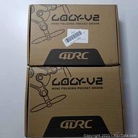 Two LOLY V2 mini folding pocket drones in original brown cardboard boxes with logo and model text