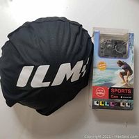 ILM helmet cover with white logo and the packaging box of the Sports Cam showing features and waterproof capability.