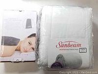Sunbeam Heated Mattress Pad Twin size in packaging and Pure Enrichment Heating Pad box showing product image and size details.