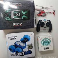Lot showing all items including the Hosim RC car box, the helicopter with remote, stunt car and UFO drone boxes.