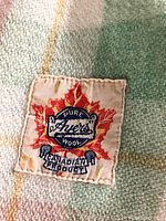 Close-up of the Ayres label sewn into the wool blanket showing brand logo, text, and maple leaf indicating Canadian product.