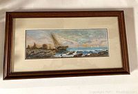 Full view of framed watercolor showing coastal sailboat scene with rocky shore and cloudy sky.