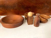 Overview of nine teak items including large and small bowls, wooden holder with sphere, cylindrical container