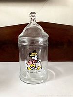 Full view of clear glass canister with domed lid showing vintage Mickey Mouse design and text.