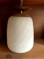 Full view of the mid-century modern ceiling fixture showing swirled white glass shade and metal canopy with wiring.