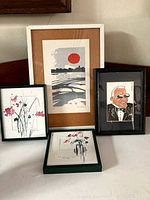 Photo of all four framed art pieces arranged together, showing variety in art styles and frames.