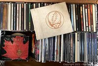 Photo showing a packed box of CDs including the Grateful Dead hardcover with lightning bolt skull and assorted CDs in jewel cases and paper sleeves.