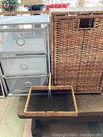Metal mesh drawer unit with three drawers next to a large woven wicker hamper and small woven basket on table