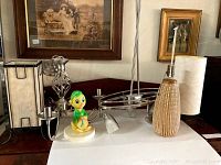 View showing six lighting fixtures including a beige rectangular wall sconce, a white ceramic cartoon character lamp base, a woven wicker lamp base, and a silver metal twisted design wall sconce.