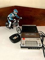 Vintage tape recorder, remote control BMX bike toy, and BMX remote on table
