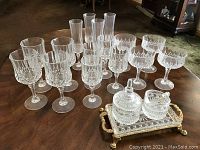 Full set of crystal glasses with sugar and creamer on small tray displayed on wooden table.