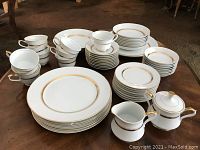 Full view of arranged china set showing plates, cups, saucers, serving pieces on wooden table.
