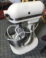 Front angled view of the KitchenAid mixer with stainless steel bowl and wire whisk attachment inside the bowl.