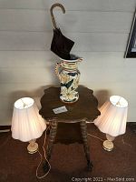 Full view of the claw foot table with umbrella stand on top and two lamps on either side, showcasing the size and arrangement of items in the lot.