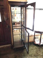 Image showing the cabinet with doors open revealing glass shelves and interior lighting features.