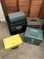 Photo showing five assorted lockboxes of different colors and sizes arranged on floor near closet doors.