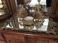 Overall view of mirrored tray with decorative accessories on dresser surface