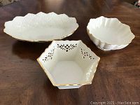 Angled view of all three bowls on table showing shape and gold-trimmed edges