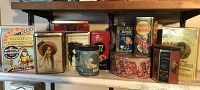 Overall view of assorted vintage advertising tins on shelf showing front and side labels