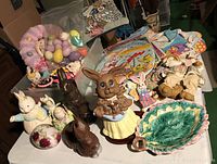 Overall view of vintage Easter decorations including ceramic bunnies, stuffed animals, plastic eggs, and cardboard cutouts