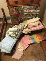 Full assortment of vintage linens displayed on floor with two themed Irish Life blankets propped behind. Includes towels, blankets, sheets, pillow cases, and dish towels.