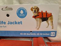 Close-up of the size and brand label showing the life jacket fits dogs 55-85 lbs with 28-32 inch girth, labeled LG size.