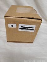 Photo of the original plain brown cardboard box for the TP-Link AC750 WiFi Extender with product and shipping labels visible.