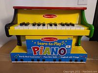 Front view of the yellow wooden Melissa & Doug Learn-to-Play Piano.