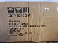 Cardboard box packaging with Zenith Home Corp branding and product details: Large ORB aluminum caddy, item number E7402ALHB, color ORB (oil-rubbed bronze).