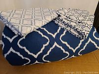 Bedsure 4-piece queen comforter set folded and stacked showing comforter, flat sheet, and two pillowcases in blue and white ikat pattern.