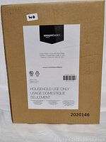Photo of the brown cardboard box packaging with Amazon Basics label and product details including household use specification.