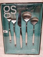 Front view of the flatware set in original packaging showing 5 pieces: fork, salad fork, knife, soup spoon, and teaspoon.