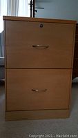 Photo of front view of two-drawer wood and MDF file cabinet with metal handles and lock on top drawer