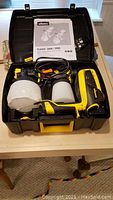 Open black carrying case showing Wagner Flexio 3000 paint sprayer with attached container, additional paint container, power cord, and owner's manual inside.