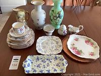 Full lot including plates, vases, serve plates, cup and saucer, and decorative items displayed on table