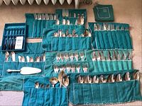 Overview of sterling flatware pieces arranged in green fabric rolls