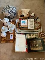 Full view of lot including bone china tea set, trays, placemats, tea cozy, and small decorative items arranged on floor.