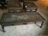 Three wooden tables (one coffee table and two end tables) displayed together on carpet.
