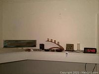 Photo showing corner shelf with multiple office decor items including decorative clock, candle holder, letter holder, paper clip holder, and digital clock.