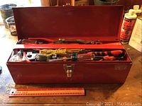 Metal red toolbox open showing hand tools including pliers and red screwdriver handles